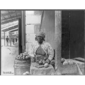  Old African American woman sitting on a street corner selling fruit 